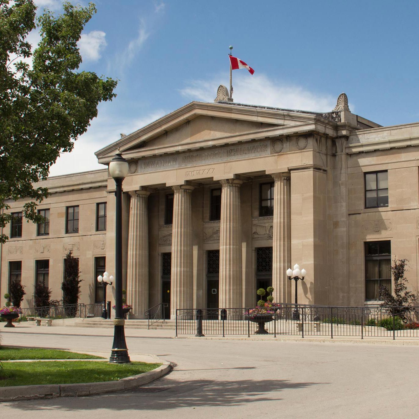 A large concrete building with pillars with the canadian flag on the top