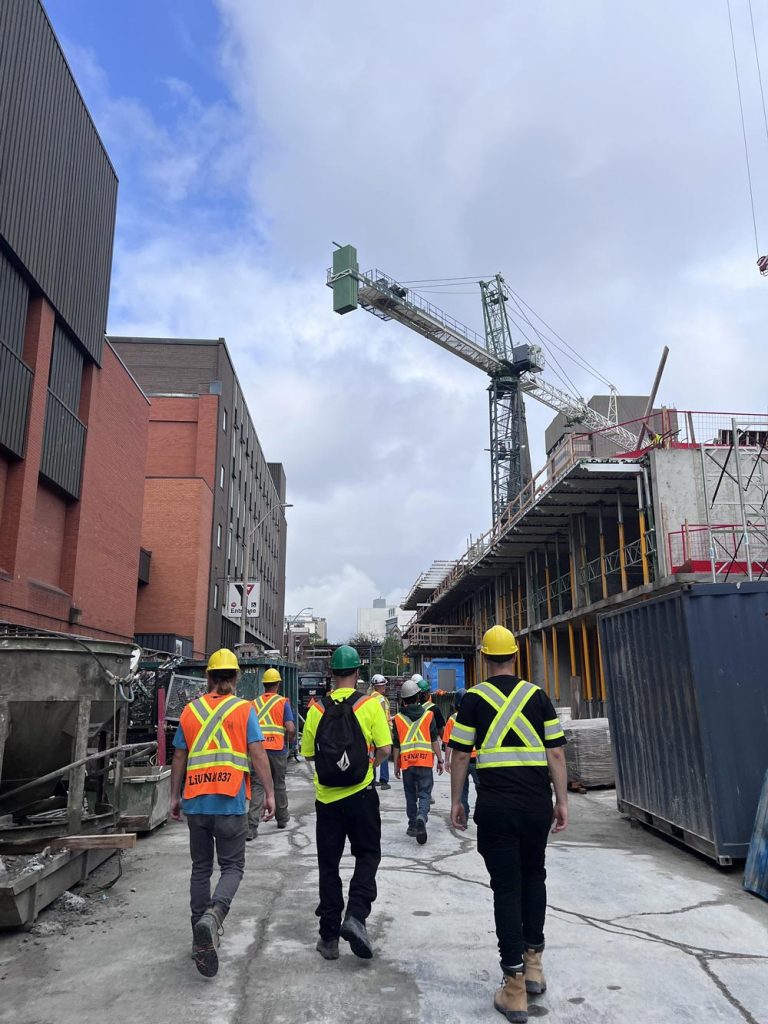 A group of construction workers walking towards a construction site.