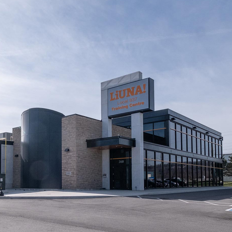 A large building featuring dark black windows, a distinctive orange stripe, and textured brick accents.